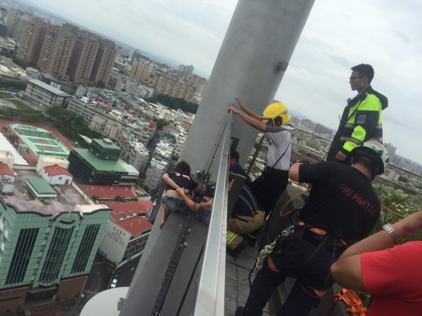 woman on roof ledge of high-rise building police and firefighters