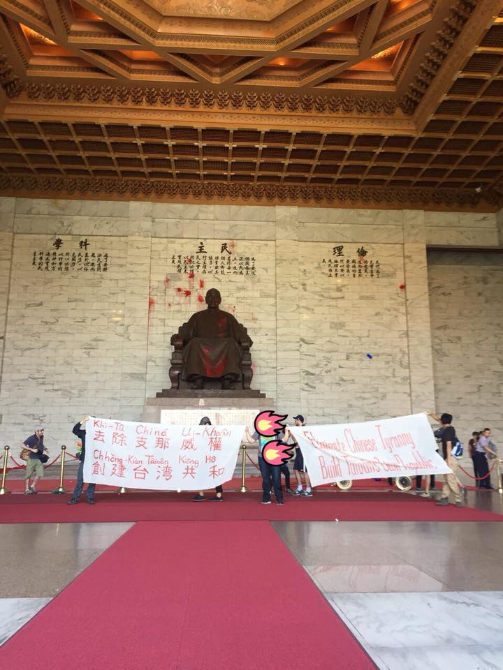 protesters hold banners in front of defaced statue of CKS