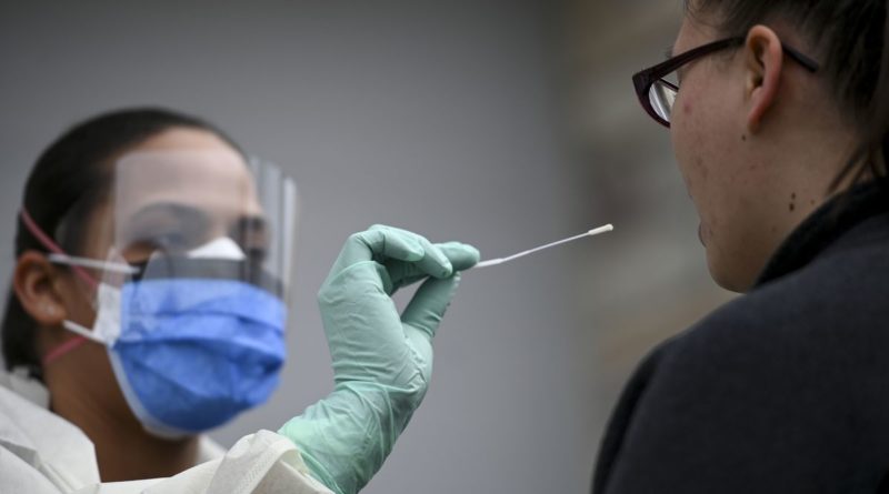 medical worker about to swab inside somebody's mouth